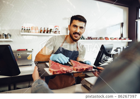 Butcher's shop seller helps to choose product to woman customer 86267397