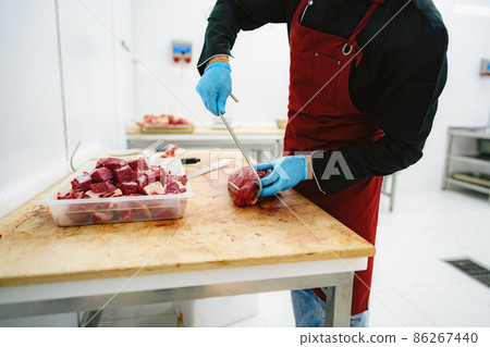 Butcher man holding meat on hook to cut and sell it 86267440