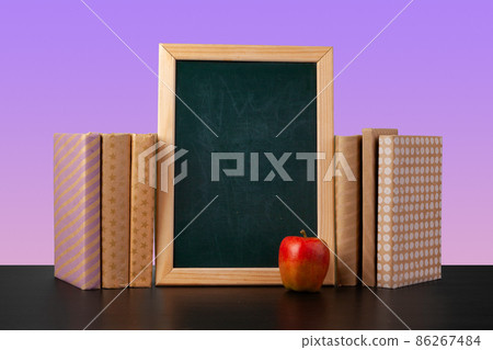 Blackboard and stacked books against colored background Blackboard and stacked books against colored background 86267484