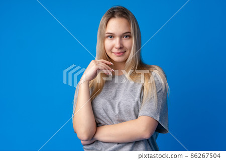 Pretty smiling girl portrait against blue background in studio 86267504