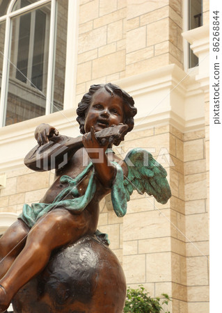 Bronze statue of an angel playing a musical instrument Bronze statue of an angel playing a musical instrument 86268844