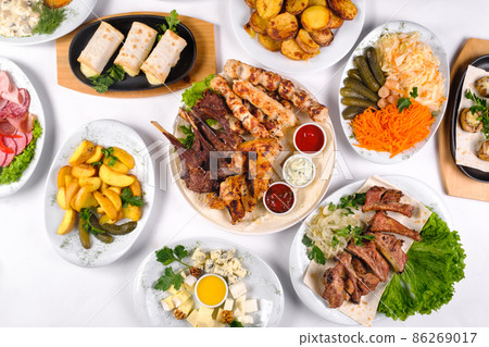 A covered table with many different dinner dishes. Lots of food on a white isolated background 86269017