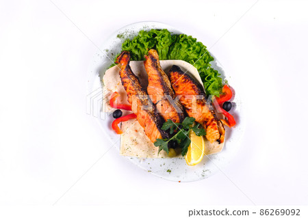 Fried fish with vegetables on a plate on a white isolated background 86269092