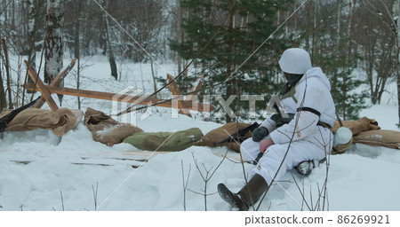 Multiple shots. Man Dressed As German Wehrmacht Infantry Soldiers In World War II Hidden Sitting With Weapon In An Ambush In Trench In Winter Day Multiple shots. Man Dressed As German Wehrmacht Infantry Soldiers In World War II Hidden Sitting With Weapon In An Ambush In Trench In Winter Day 86269921