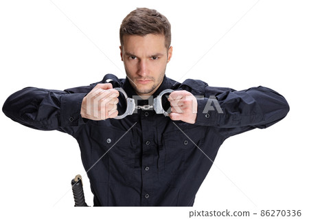Half-length portrait of young male policeman officer wearing black uniform posing isolated on white background. Concept of job, caree, law and order. Half-length portrait of young male policeman officer wearing black uniform posing isolated on white background. Concept of job, caree, law and order. 86270336