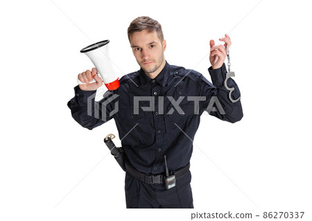 Studio shot young happy man, policeman officer wearing black uniform posing isolated on white background. Concept of job, caree, law and order. Studio shot young happy man, policeman officer wearing black uniform posing isolated on white background. Concept of job, caree, law and order. 86270337