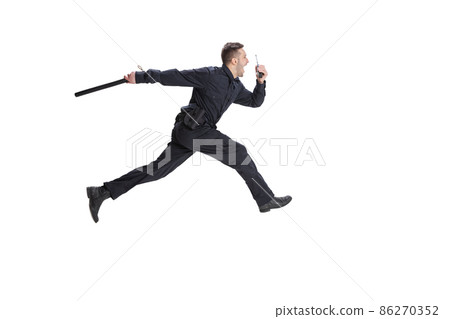 Dynamic portrait of young man, policeman officer wearing black uniform running isolated on white background. Concept of job, caree, law and order. Dynamic portrait of young man, policeman officer wearing black uniform running isolated on white background. Concept of job, caree, law and order. 86270352