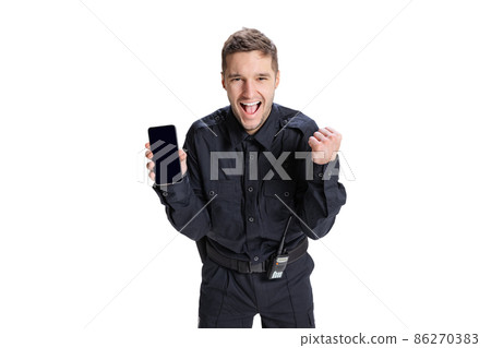 Portrait of young man, policeman officer wearing black uniform using phone isolated on white background. Concept of job, caree, law and order. Portrait of young man, policeman officer wearing black uniform using phone isolated on white background. Concept of job, caree, law and order. 86270383
