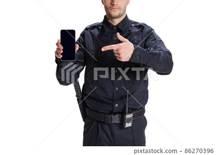 Portrait of young man, policeman officer wearing black uniform using phone isolated on white background. Concept of job, caree, law and order. Portrait of young man, policeman officer wearing black uniform using phone isolated on white background. Concept of job, caree, law and order. 86270396