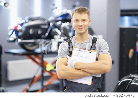 Qualified maintenance center worker in uniform posing on motorbike background 86270475