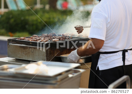 Metal construction for frying meat in nature, male chef do grill 86270527