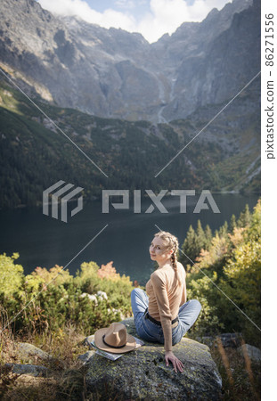 Young woman on a hiking trip sitting on a rock 86271556