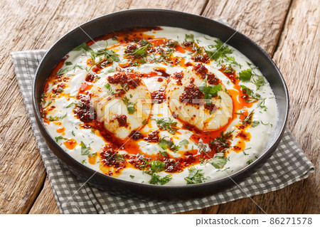 Cilbir is a Turkish eggs containing garlicky yogurt, poached eggs, and spiced melted butter in the plate. Horizontal Cilbir is a Turkish eggs containing garlicky yogurt, poached eggs, and spiced melted butter in the plate. Horizontal 86271578