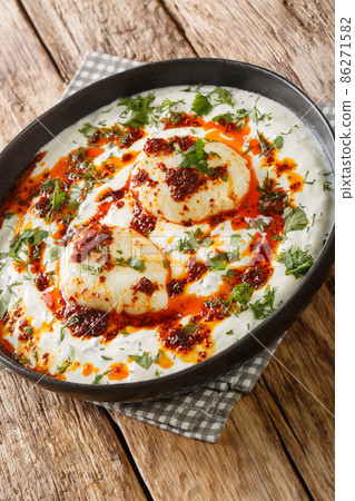 Turkish dish of poached eggs with yogurt closeup in the plate. Vertical Turkish dish of poached eggs with yogurt closeup in the plate. Vertical 86271582