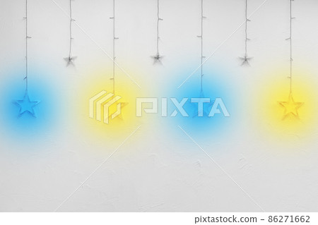 Colored bright garlands in the form of stars on a white empty wall of the interior background decor Colored bright garlands in the form of stars on a white empty wall of the interior background decor 86271662