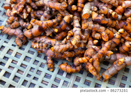 Turmeric roots on wooden spoon on white background. Turmeric roots on wooden spoon on white background. 86273281