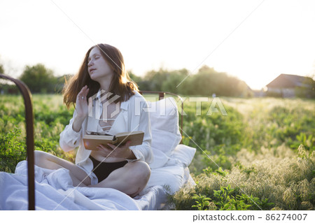 girl reading a book in bed among the fields at sunset girl reading a book in bed among the fields at sunset 86274007