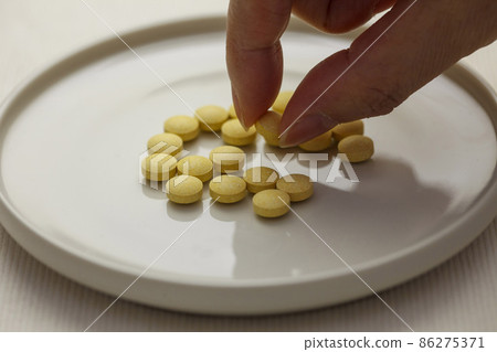 Lots of yellow supplement grains on a white plate 86275371