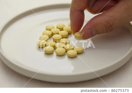 Lots of yellow supplement grains on a white plate 86275373