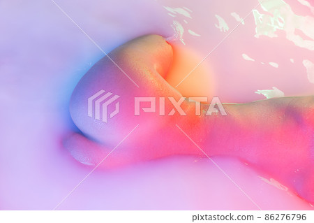 Closeup female hips, bottocks in the milk bath with soft pink neon glow. Beauty, fashion, style, bodycare, spa concept. Closeup female hips, bottocks in the milk bath with soft pink neon glow. Beauty, fashion, style, bodycare, spa concept. 86276796