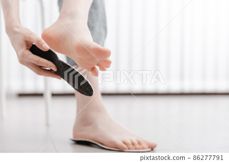 Woman fitting orthopedic insole indoors, close up. Girl holding an insole next to foot at home. Orthopedic insoles. Foot care banner. Flat Feet Correction. Treatment and prevention of foot diseases. Woman fitting orthopedic insole indoors, close up. Girl holding an insole next to foot at home. Orthopedic insoles. Foot care banner. Flat Feet Correction. Treatment and prevention of foot diseases. 86277791