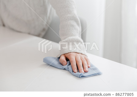 Cleaning the table with a blue microfiber cloth. Sanitize surfaces prevention in hospital and public spaces against coronavirus. Woman hand using wet wipe at home. Cleaning the room. Cleaning the table with a blue microfiber cloth. Sanitize surfaces prevention in hospital and public spaces against coronavirus. Woman hand using wet wipe at home. Cleaning the room. 86277805