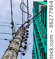 An old shabby electric pole against the sky and the building 86277864