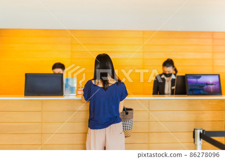 Woman guest check in with receptionist at hotel counter. 86278096