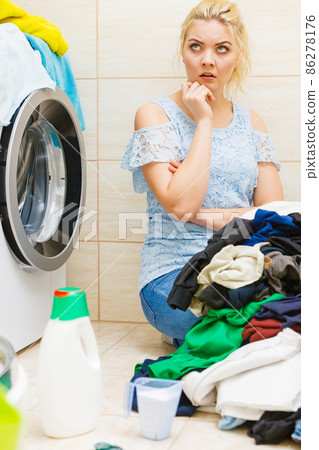 Unhappy girl sorting dirty clothes laundry. Unhappy girl sorting dirty clothes laundry. 86278176