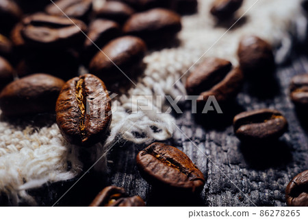 Macrophotography of coffee beans lie on textured wood and burlap. Fresh harvest aromatic coffee 86278265