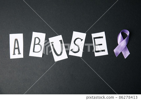 Purple ribbon and word ABUSE on black background, flat lay. Domestic violence awareness Purple ribbon and word ABUSE on black background, flat lay. Domestic violence awareness 86278413