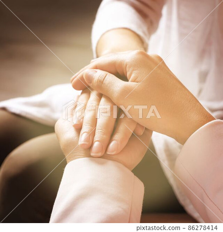 Volunteer holding hands with woman in sunlit room, closeup 86278414