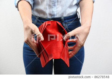 Woman showing empty wallet on light background, closeup 86278548