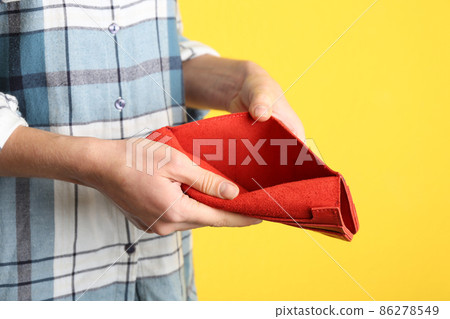 Woman showing empty wallet on yellow background, closeup 86278549