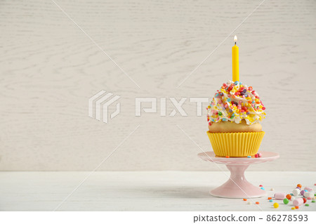 Birthday cupcake with candle on white table against wooden background. Space for text 86278593