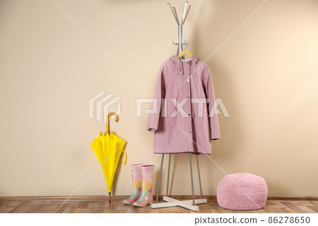 Yellow umbrella, raincoat and rubber boots near beige wall 86278650