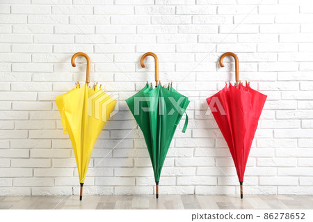 Beautiful colorful umbrellas near white brick wall 86278652