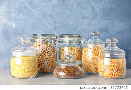 Jars with different cereals on grey marble table against light blue background Jars with different cereals on grey marble table against light blue background 86278725