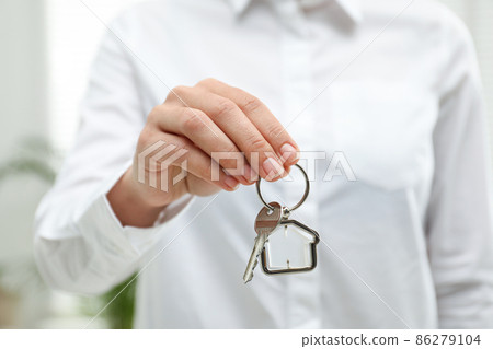 Real estate agent holding house key with trinket indoors, closeup Real estate agent holding house key with trinket indoors, closeup 86279104