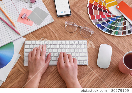 Designer working on computer at wooden table, top view 86279109