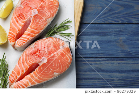 Top view of fresh raw salmon with lemon and rosemary on blue wooden table, space for text. Fish delicacy Top view of fresh raw salmon with lemon and rosemary on blue wooden table, space for text. Fish delicacy 86279329