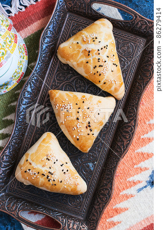 Samsa, national savory baking, usually with minced meat, cheese or vegetables as a filling, an oriental meal, Central Asia cuisine concept. Samsa, national savory baking, usually with minced meat, cheese or vegetables as a filling, an oriental meal, Central Asia cuisine concept. 86279414