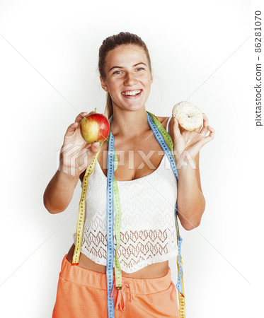 woman measuring waist with tape having choise between apple and donut isolated on white background 86281070