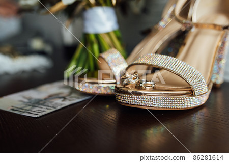 beautiful gold wedding rings on wooden table next to bouquet and shoes 86281614