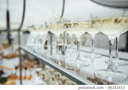 Glasses of champagne at the Banquet, white sparkling wine in wine glasses, festive mood Glasses of champagne at the Banquet, white sparkling wine in wine glasses, festive mood 86281653