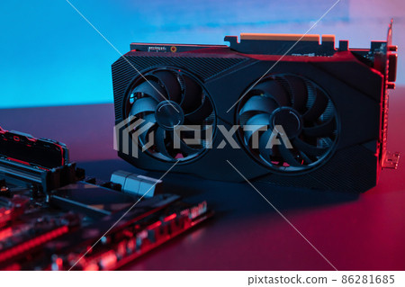 Modern graphic card lies on the desk next to motherboard Modern graphic card lies on the desk next to motherboard 86281685