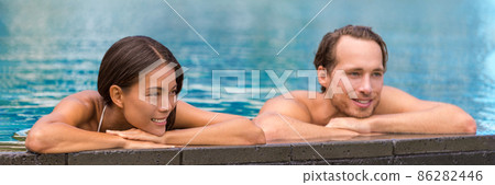 Spa retreat wellness resort couple relaxing sunbathing in hotel infinity swimming pool. Luxury travel hydrotherapy resort holidays Asian woman and man enjoying swim in water. Banner panoramic. Spa retreat wellness resort couple relaxing sunbathing in hotel infinity swimming pool. Luxury travel hydrotherapy resort holidays Asian woman and man enjoying swim in water. Banner panoramic. 86282446