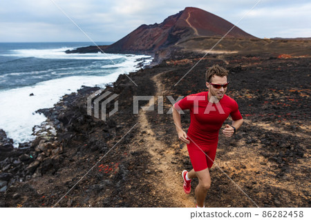 Runner man sport athlete ultra running on endurance trail race competition training on volcano cliff wearing compression clothes, sunglasses smartwatch wearable device. Runner man sport athlete ultra running on endurance trail race competition training on volcano cliff wearing compression clothes, sunglasses smartwatch wearable device. 86282458