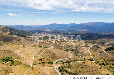 Aerial panoramic drone point of view road surrounded by lands and meadows Aerial panoramic drone point of view road surrounded by lands and meadows 86282992