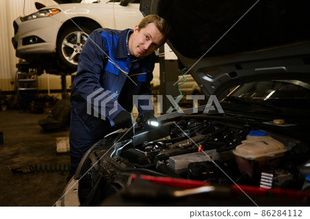 Technician automotive checking car in the garage. Auto mechanic working with engine in garage, car service technician repairing customer care at automobile service center. 86284112